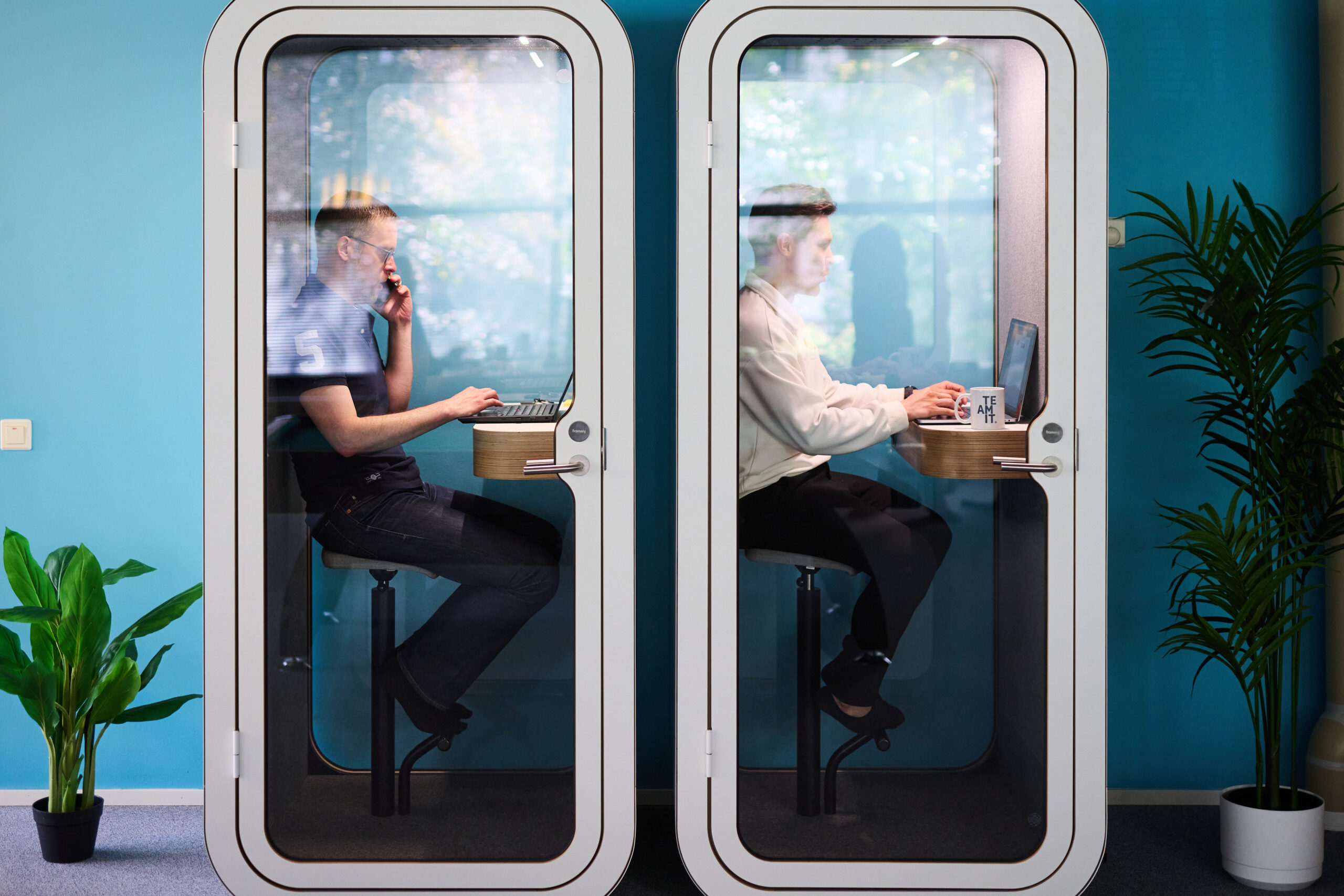 Kaksi ihmistä istuu puhelinkopeissa.